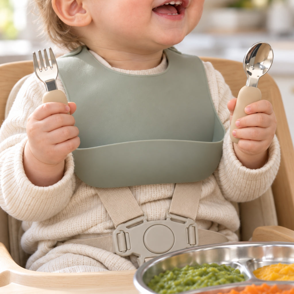 Bébé tenant sa cuillère et sa fourchette bébé inox à manche silicone