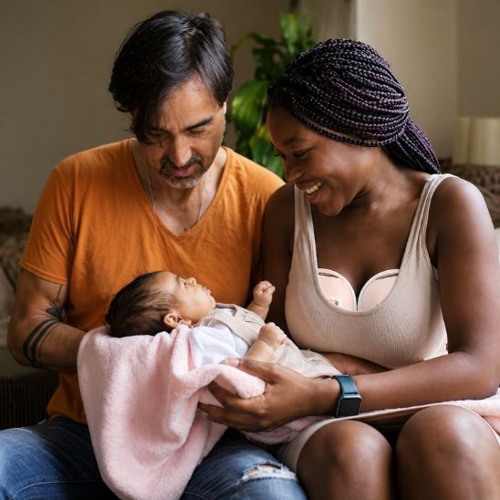 Parents heureux avec leur nouveau-né — tire-lait main libre LiberTait porté discrètement